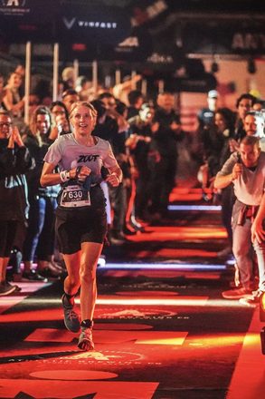 Juliet running down the finish chute of an Ironman triathlon at night