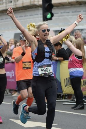 Juliet with arms in the air approaching a marathon finish line
