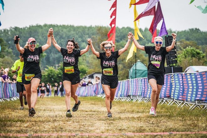 Four teammates holding hands as they cross a race finish line
